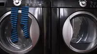 A close-up of a dark navy blue washer and dryer pair. A pair of blue and black striped socks hang from the door of the washer.