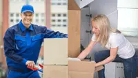 A professional worker with a cardboard box next to a woman working on her closet.