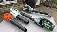 A person holds a cordless leaf blower while three others sit on a table