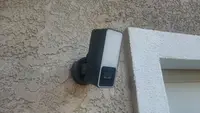 The Eve Cam Outdoor smart floodlight hangs near a residential garage