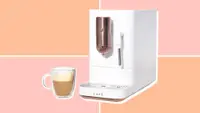 Café Affetto machine next to a latte in a glass mug, on a pink and orange backgorund.