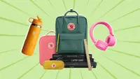 On a light green background: An orange HydroFlask water bottle, one pink and one green Fjallraven backpack, a pair of pink headphones, and a stack of notebooks.