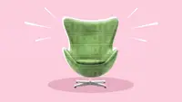 An egg chair with dollar bills overlaying it against a pink background.