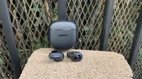 The Bose QuietComfort II earbuds with the carrying case on display in an outdoor setting.