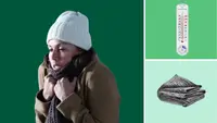 Woman bundled up in beanie, scarf, and coat sitting in living room