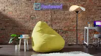 Yellow Floyd Squishy Chair in front of brick wall next to side table, and floor Y-Lamp.