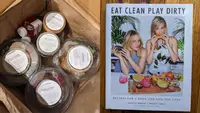 On left, individual plastic containers filled with food inside of paper bag . On right, front cover of _Eat Clean Play Dirty_ cookbook.