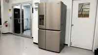 Stainless steel refrigerator with top top and two bottom doors sits inside of testing lab