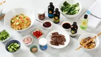 Assorted bowls of ramen, sauces and garnishments from Momofuku on granite countertop
