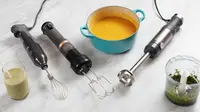 Three immersion blenders on a marble surface alongside blended soup, pesto, and a smoothie
