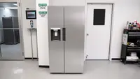 Stainless steel Midea MRS26D5AST Side-by-Side Refrigerator in front of white wall and white door.