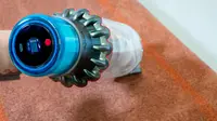 A hand holding the Dyson Gen5outsize with the LCD display screen showing while cleaning the floor