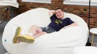A man smiling while he's laying on the bean bag.