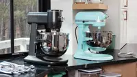 Black GE Profile and aqua KitchenAid stand mixer sit on a kitchen counter in front of a window.