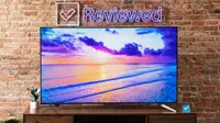 TCL Q7 QLED TV on an entertainment center, with a brick background and Reviewed sign above the TV.