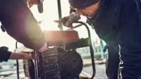 Two workers repair a portable generator.