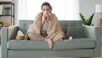 Person on couch blowing nose