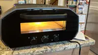 The Ooni Volt 12 pizza oven sitting on top of granite countertop.