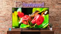 Hisense U7K Mini-LED TV sitting on top of wooden television stand in front of brick wall and Reviewed LED sign.