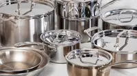 Several stainless steel pots and pans crowded together on a white surface
