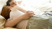 A couple asleep in bed cuddling