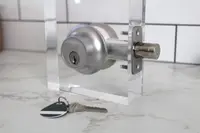 The Level Lock Plus Connect smart deadbolt set up on a test stand with a key and fob on the counter