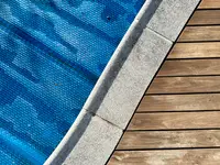 A blue solar pool cover sits on top of a pool.