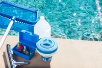 Cleaning materials for pool maintenance sitting on the edge of a pool.