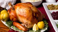 Cooked turkey on a plate with fruit and herbs.