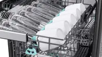 An open Samsung dishwasher with the 3rd rack pulled out to show cups and glasses, and the other 2 showing in the background.