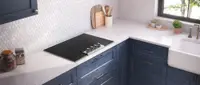 A Frigidaire Professional induction cooktop in a white kitchen counter near a sink and blue cabinets.