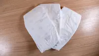 Three white Pampers Amore diapers fanned out on a wooden surface