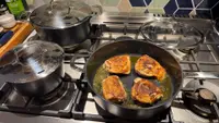 Alva Ceramic Cookware Set sitting on top of spider-burner stovetop with a pan cooking chicken.