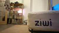 White Ziwi mattress shown on the right, with a bookcase and spherical lamp in the background.