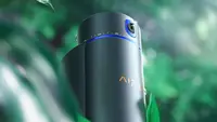 An Aiper IrriSense 2 in the foreground surrounded by blurred leaves