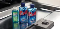 Bottles of rinse aid on an open dishwasher door.