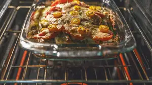 A rectangular Pyrex dish filled with food bakes in an oven.