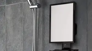 A fogless shower mirror being used for music and for a man to shave.
