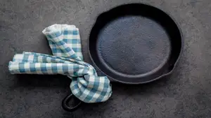 Dirty cast iron with blue and white checkered towel tied to the handle