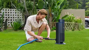 A blonde man in beige clothes attaches a hose to his Aiper IrriSense 2