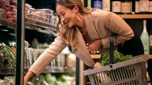 A woman selects produce at a supermarket.