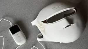 White Megelin LASER & LED mask and remote on grey surface.