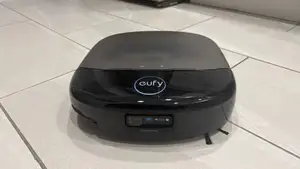 A black robot vacuum on a beige tile floor