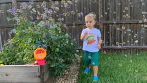 A toddler runs through bubbles outside