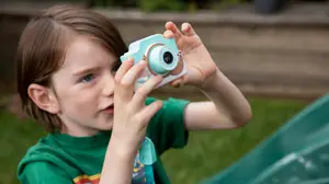 A young child happily takes a photo with their Kidamento kids digital camera