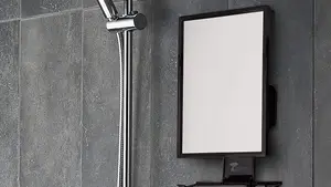 A fogless shower mirror being used for music and for a man to shave.