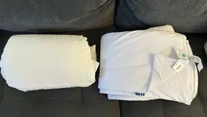 White Cooloxy Breathable Cooling Comforter and SleepEase Cooling Comforter Set next to each other on a dark grey couch.