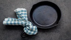 Dirty cast iron with blue and white checkered towel tied to the handle