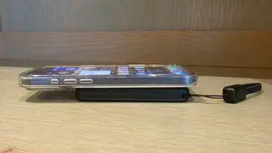 Black INIU SnapGo Air Power Bank laying underneath a smart phone on a wooden surface.