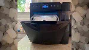 Black Govee Smart Countertop Ice Maker 2 on a kitchen counter, open and showing ice inside.